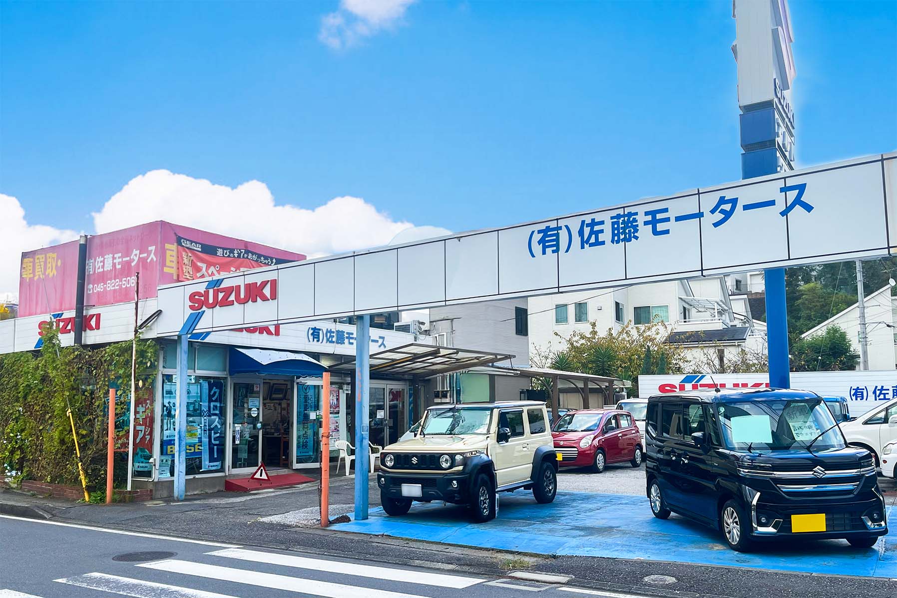 佐藤モータースの店舗外観と、手前に並ぶ車両
